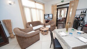 A furnished room with wicker furniture, a television, a wine rack, and a table set for dining. - Al Ritrovo Ristorante & Albergo (San Vito Lo Capo)