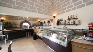 A restaurant with a brick ceiling, a bar area with shelves of bottles, and a glass display case with food. - Al Ritrovo Ristorante & Albergo (San Vito Lo Capo)
