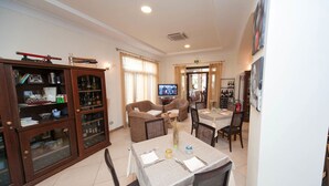A dining area with a television, dining table, chairs, and a cabinet with bottles. - Al Ritrovo Ristorante & Albergo (San Vito Lo Capo)