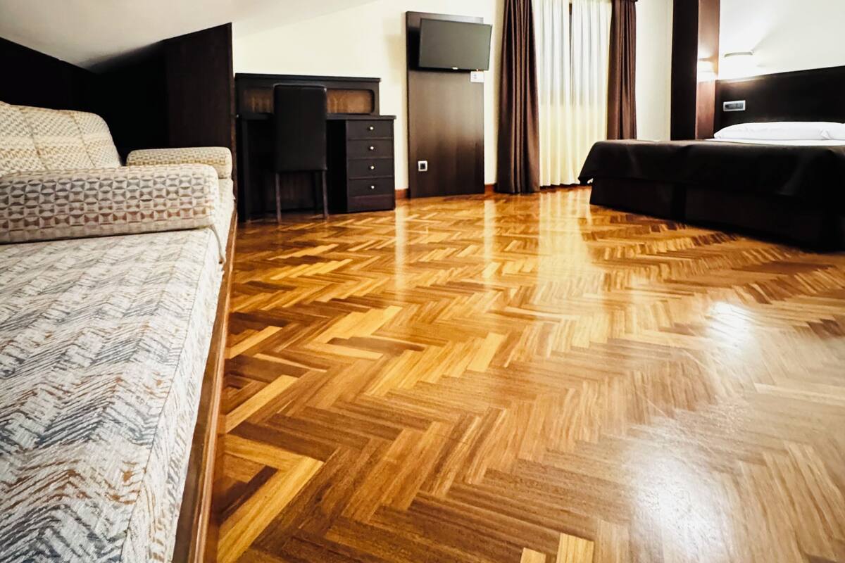 A hotel room with a large bed, a desk, a television, and a wardrobe.