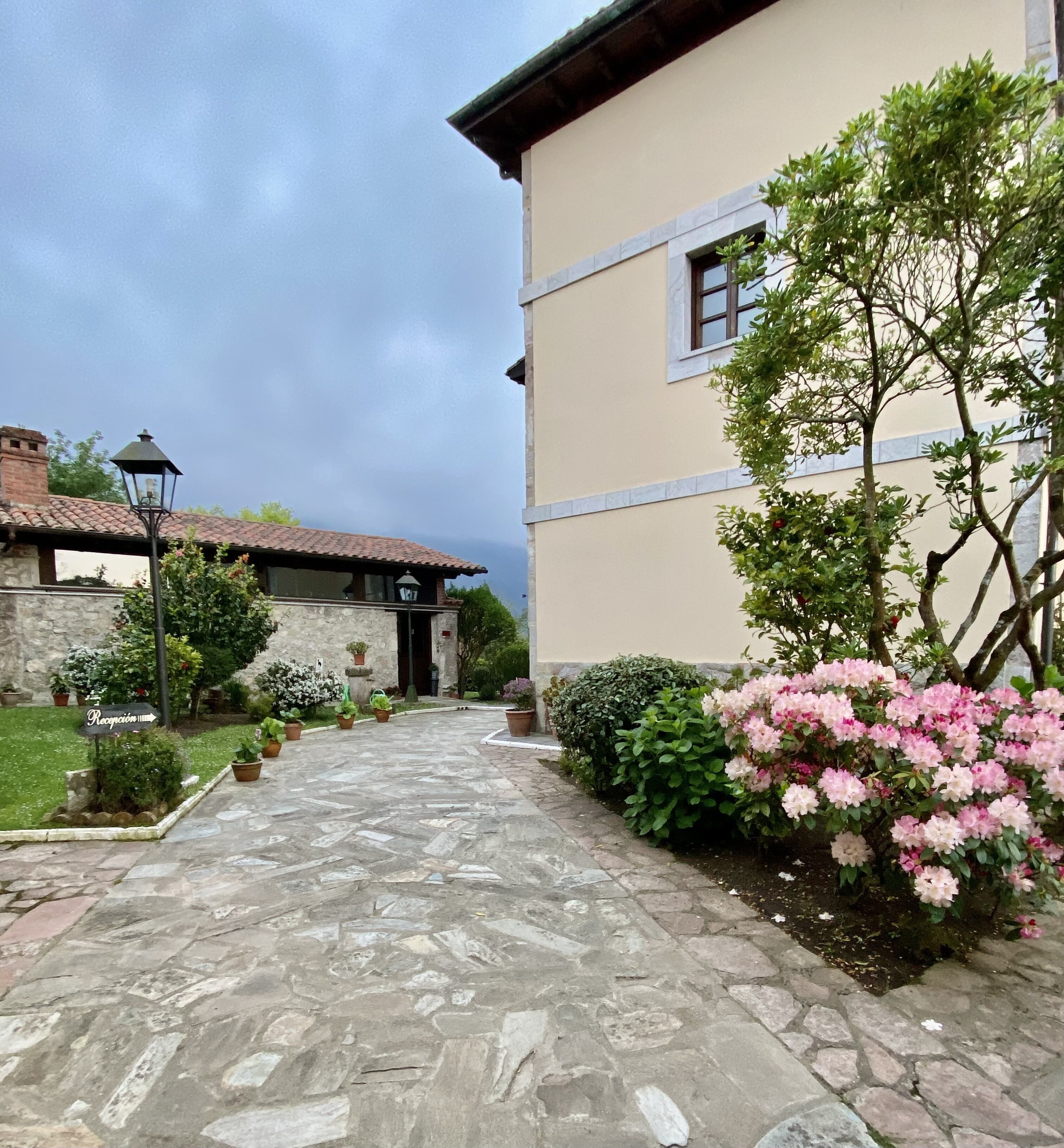 A stone pathway leading to a building with a tiled roof and a sign indicating a reception area.