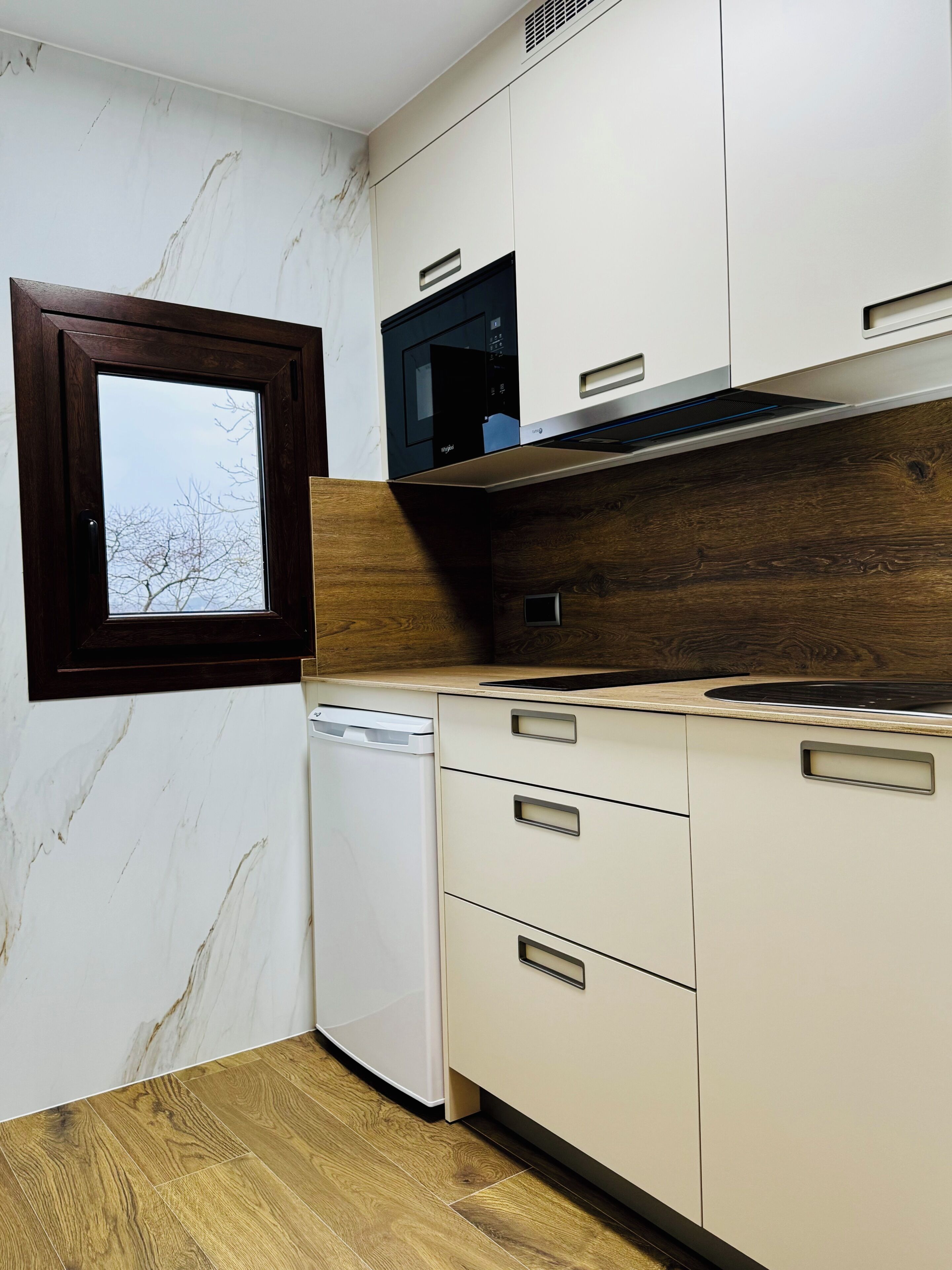 A kitchen with a built-in microwave, wooden countertop, and a window with a view of bare trees.