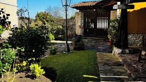 Un patio con un camino de piedra que conduce a un portón de madera, rodeado de follaje y un farol.