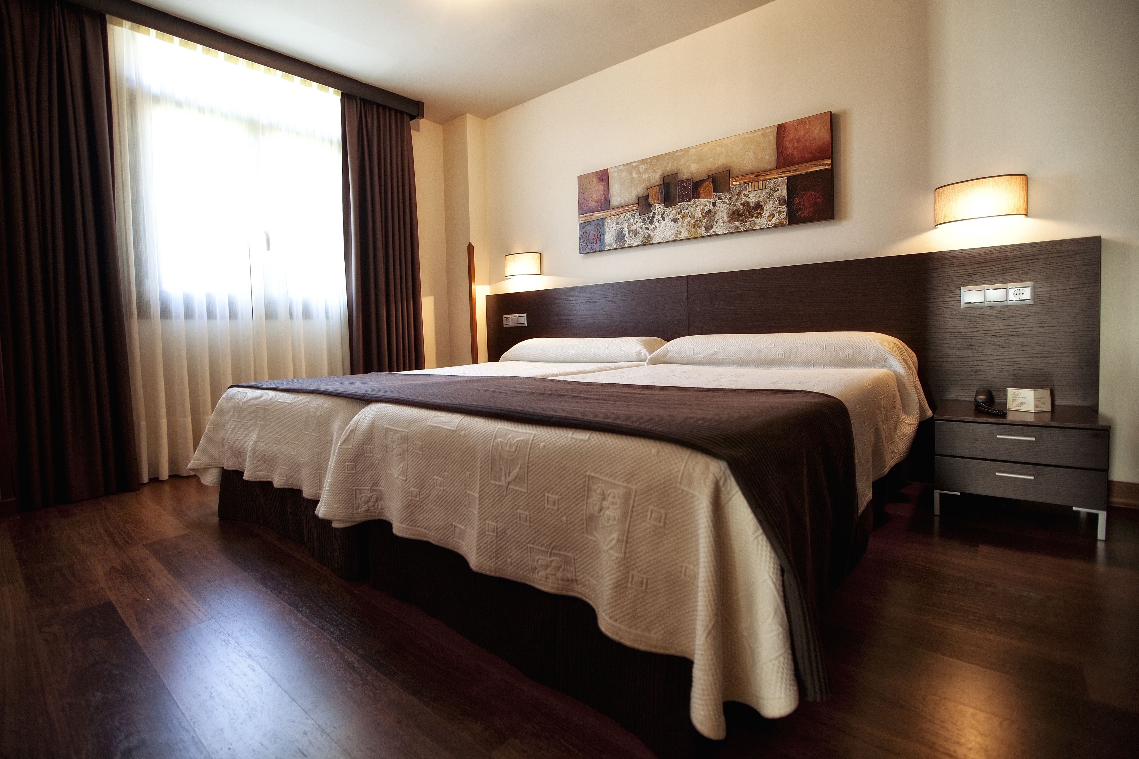 Una habitación de hotel con una cama grande, una mesita de noche, una lámpara y un cuadro en la pared.