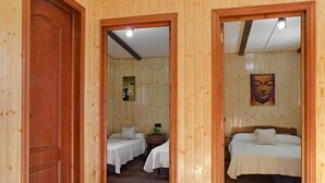 Habitación con paneles de madera, dos camas, una mesita de noche y una obra de arte colgada en la pared.
