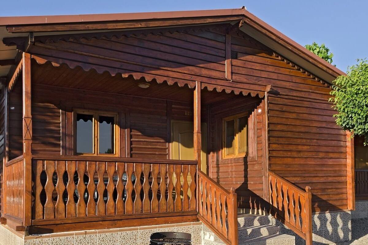 A wooden cabin with a porch and steps leading to the entrance.