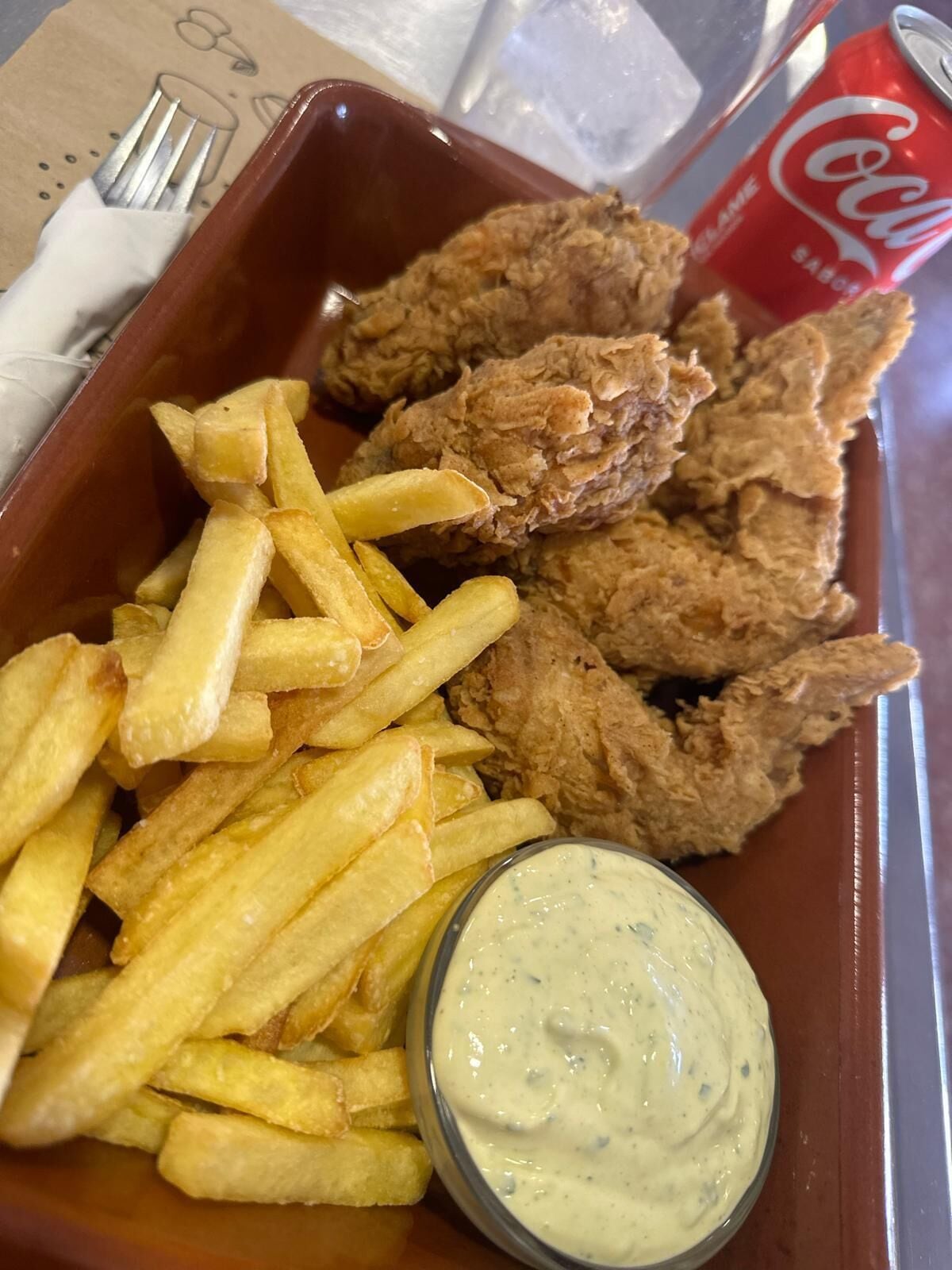A tray with fried chicken, French fries, and a dipping sauce.