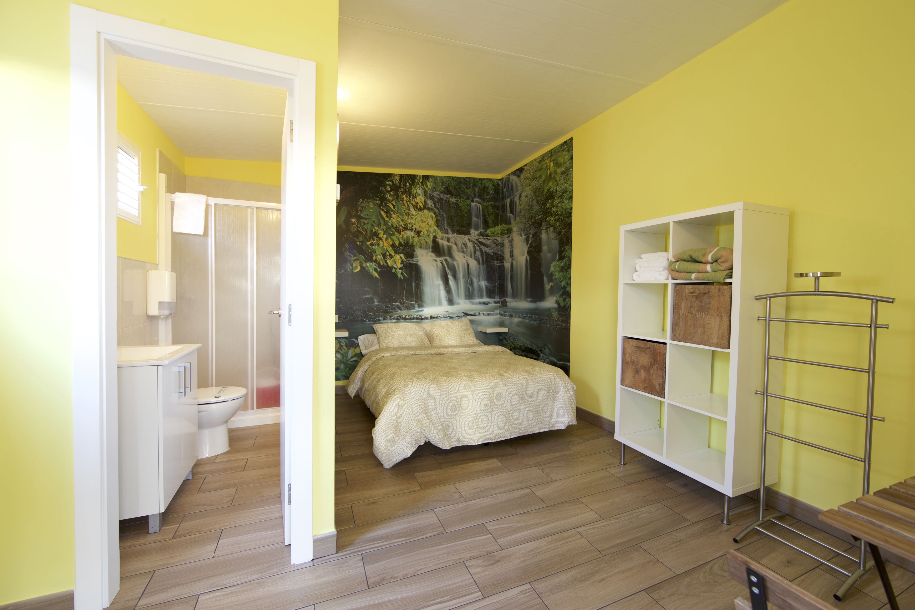 A bedroom with a bed, a white wardrobe, and a bathroom with a toilet and sink.