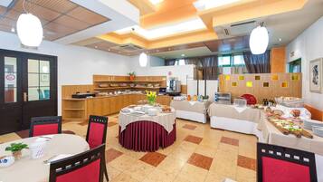 Un espace repas comprenant plusieurs tables, des chaises et un buffet.