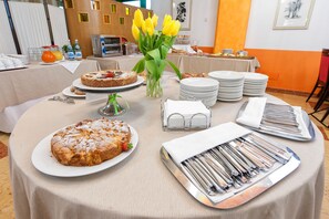 Une table de buffet garnie de divers plats, notamment un gâteau et une assiette de fruits, ainsi qu'un vase rempli de fleurs jaunes.