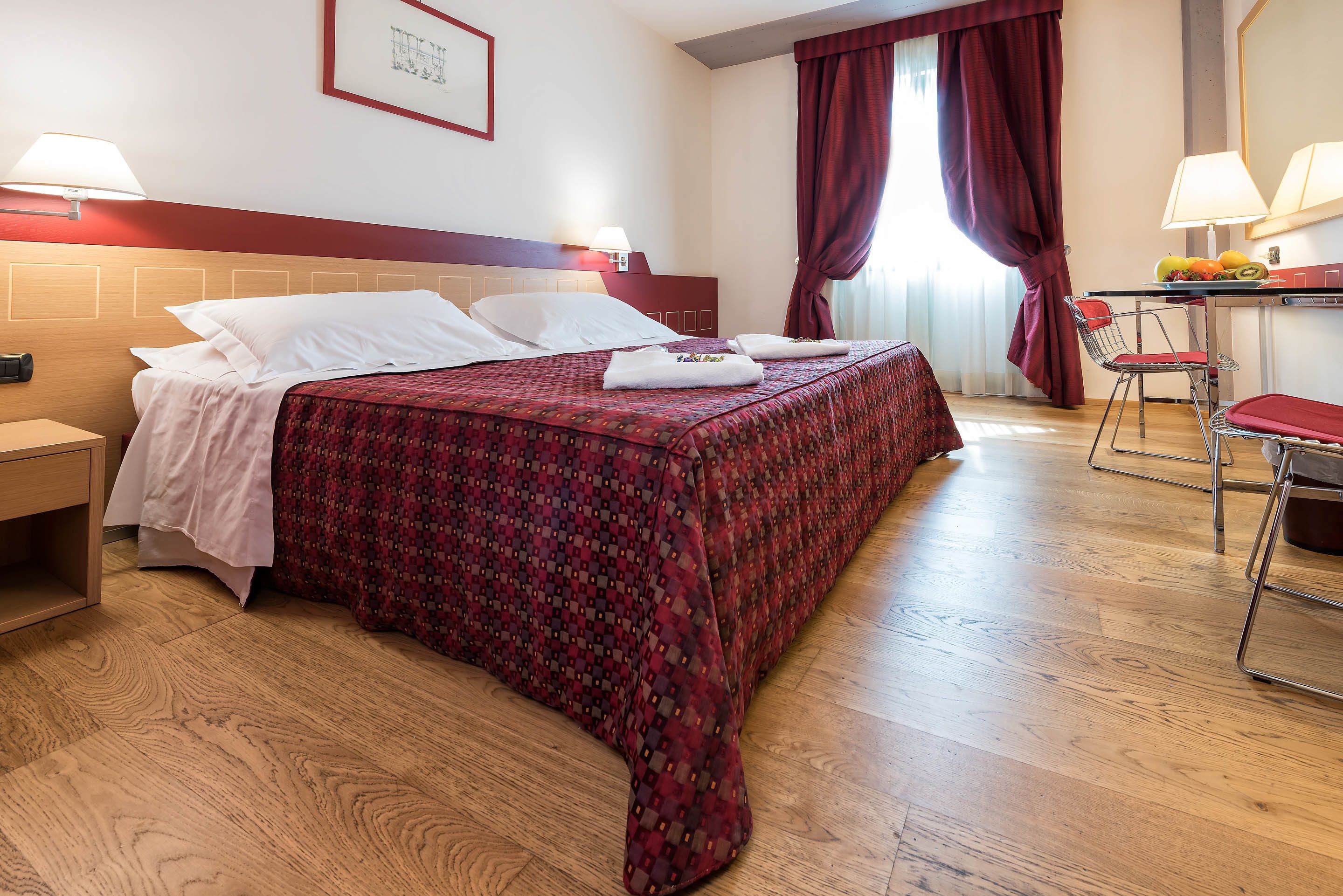 Habitación de hotel con una cama grande, un escritorio con silla y una ventana con cortinas.