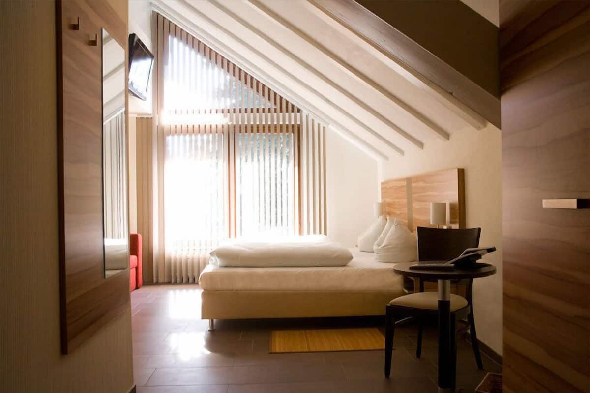 A modern bedroom with a bed, a desk, and a chair.