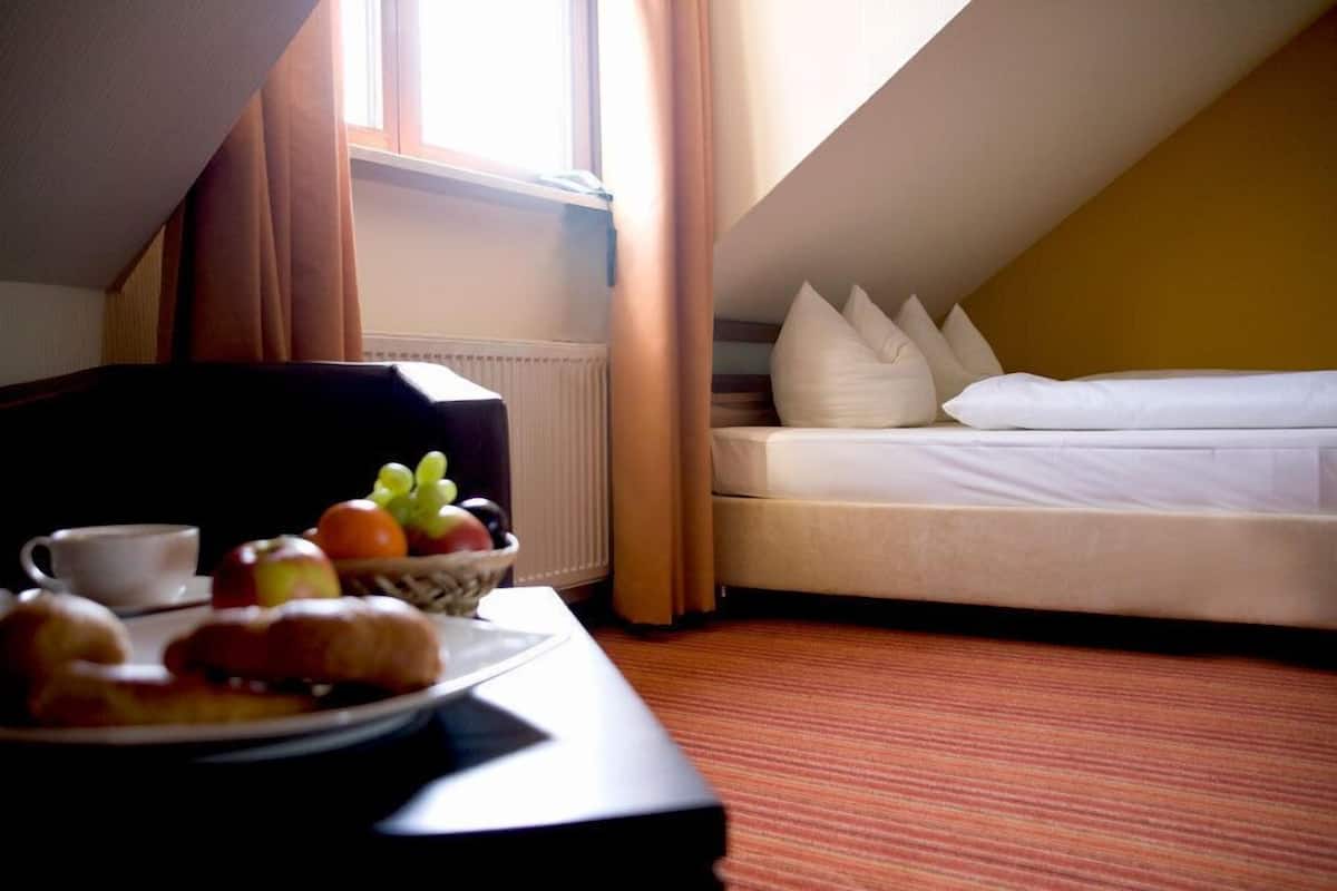 A hotel room with a bed, a dining table with breakfast, and a window with curtains.