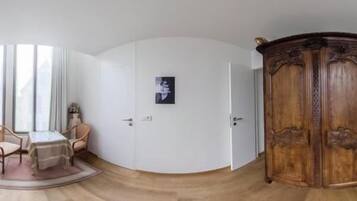 A room with a bed, a wooden wardrobe, a small table with chairs, and a door.