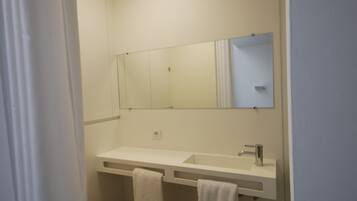 A bathroom with a white sink, a mirror, and two towels hanging on a rack.