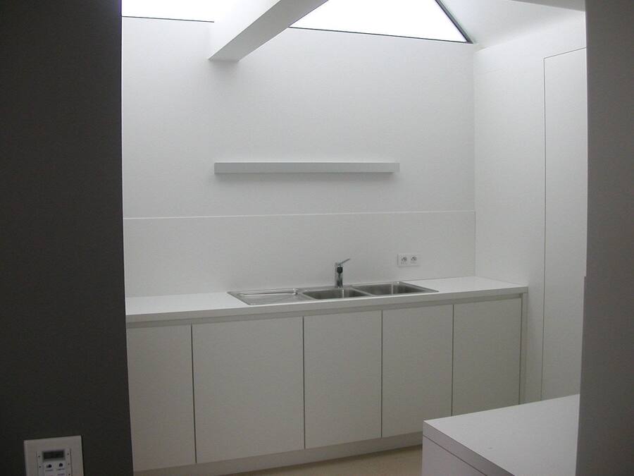 Een moderne keuken met witte kastjes, een roestvrijstalen spoelbak en een dakraam erboven.