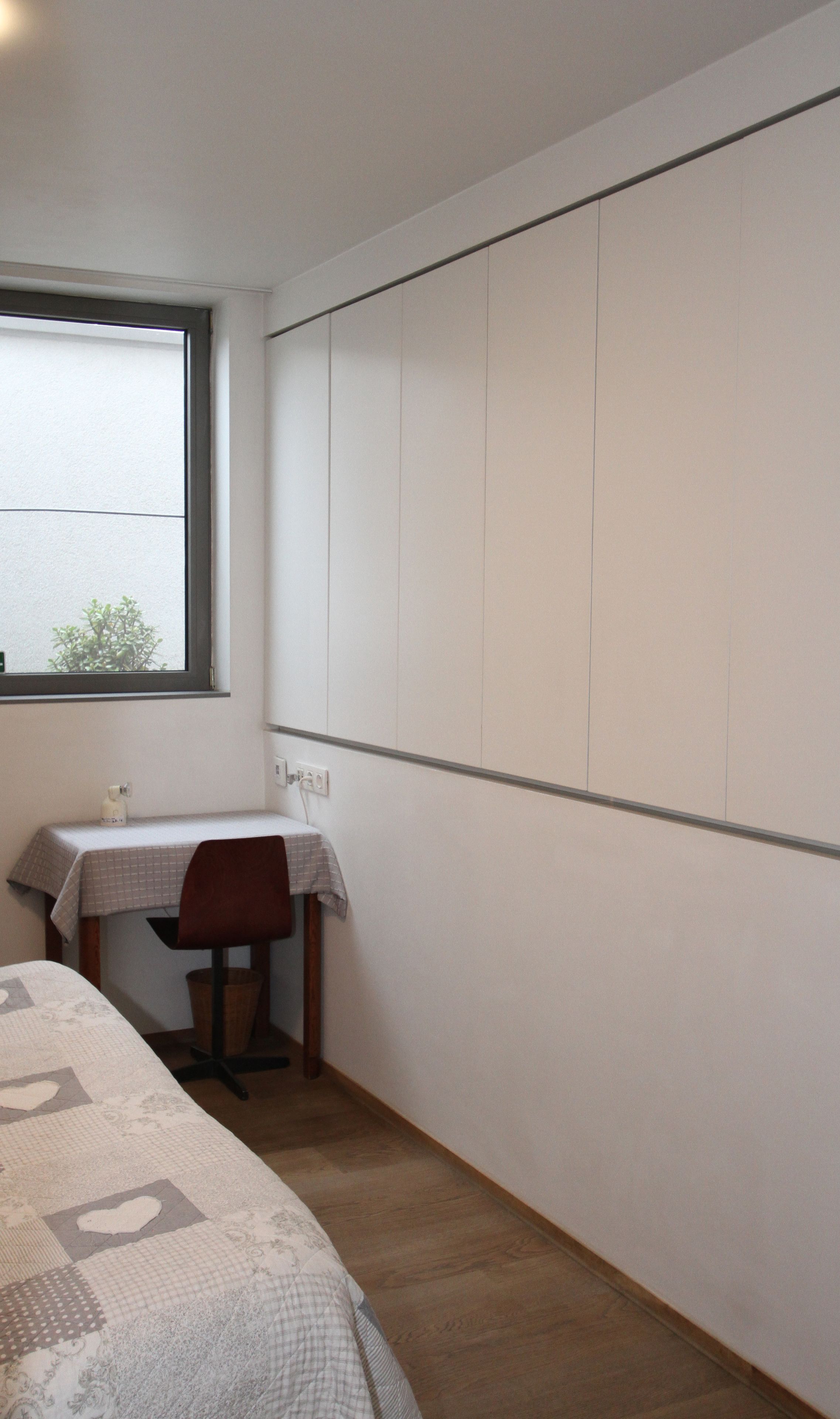 Een kleine kamer met een bed, een bureau en een raam.