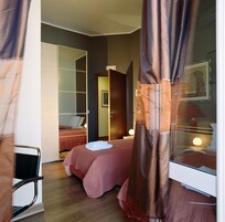 A bedroom with a bed, a wardrobe, and a bedside table with a lamp.