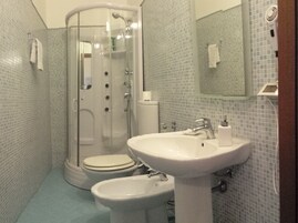 A bathroom with a glass-enclosed shower, a sink, a bidet, and a toilet.