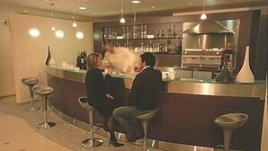 A bar area with stools, a counter, and a shelf with bottles. - Hotel Cecere (Mottola)