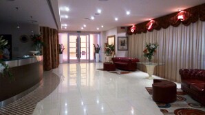 A hotel lobby with a reception desk, a red leather sofa, and a patterned carpet. - Hotel Cecere (Mottola)
