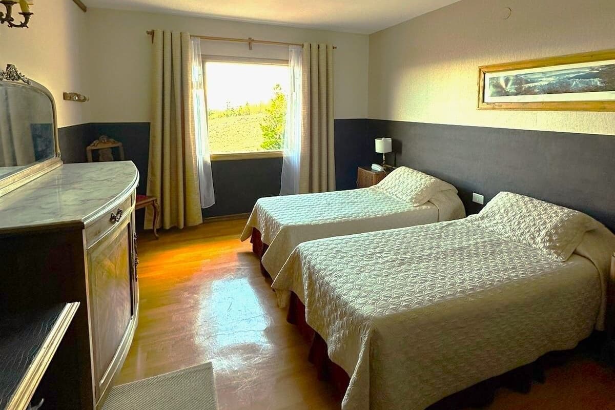 Habitación de hotel con dos camas, un escritorio y una ventana con cortinas.