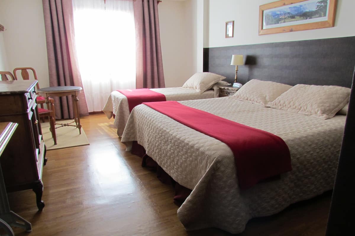 Una habitación de hotel con dos camas, un escritorio, una silla y una lámpara.