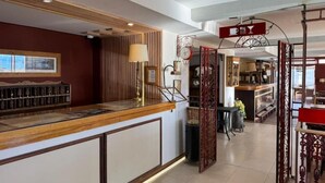 A hotel reception area with a wooden counter, a red decorative partition, and a view of the interior space. - Hostería Meulen (El Calafate)