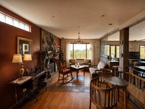 A spacious living room with a fireplace, a dining area, and a kitchen visible through an open door.