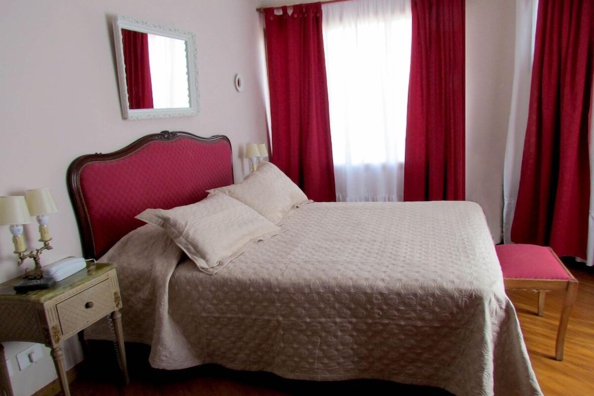 Une chambre à coucher avec un lit, une table de chevet, une lampe et un miroir au mur.