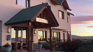 A two-story building with a green roof, a wooden porch, and a sign that reads "MEULEN Hostería y Apart." - Hostería Meulen (El Calafate)