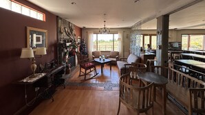 A spacious living area with a fireplace, a dining table, and a kitchen area visible through an open door. - Hostería Meulen (El Calafate)