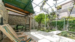 Un espace extérieur aménagé, abrité et doté de murs en pierre et d’une structure en verre.