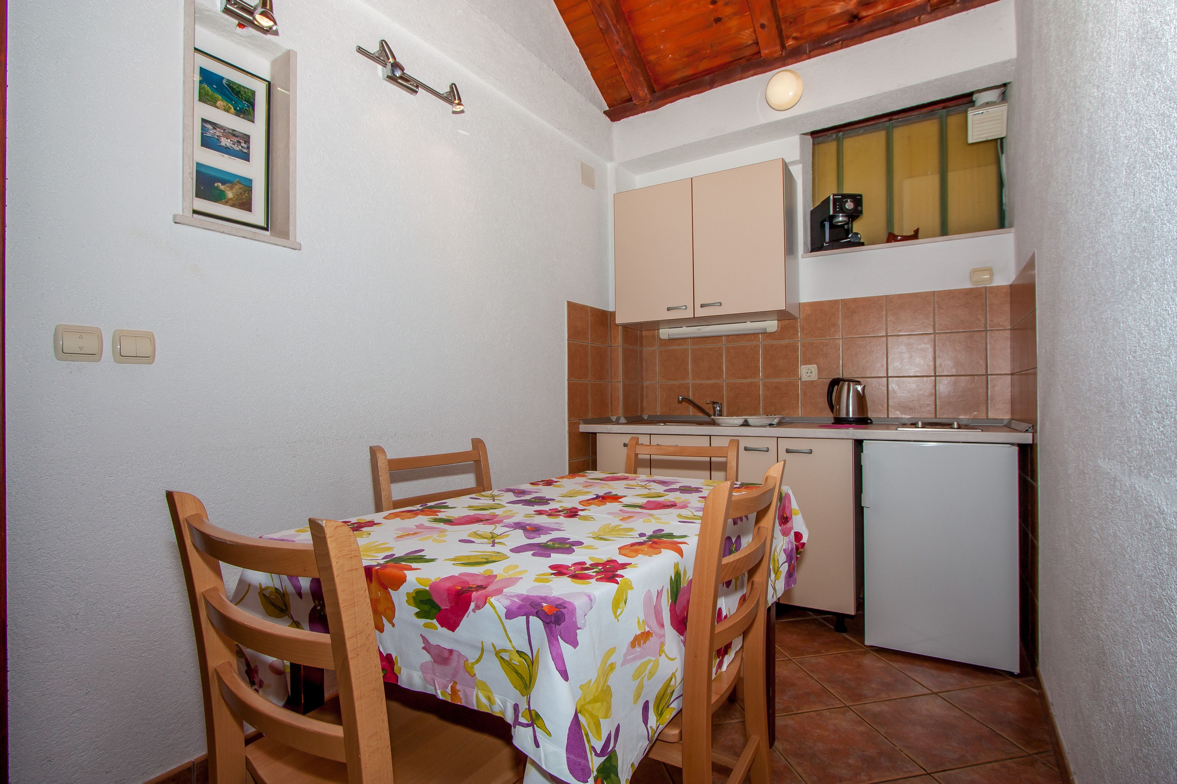 Una cocina compacta con mesa, sillas, refrigerador y una ventana sobre el fregadero.