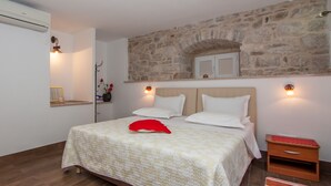 Une chambre à coucher comprenant un lit, une table de chevet, une étagère fixée au mur et un mur en pierre.