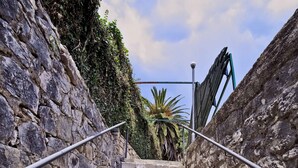 Un escalier en pierre avec des rampes métalliques, qui monte.