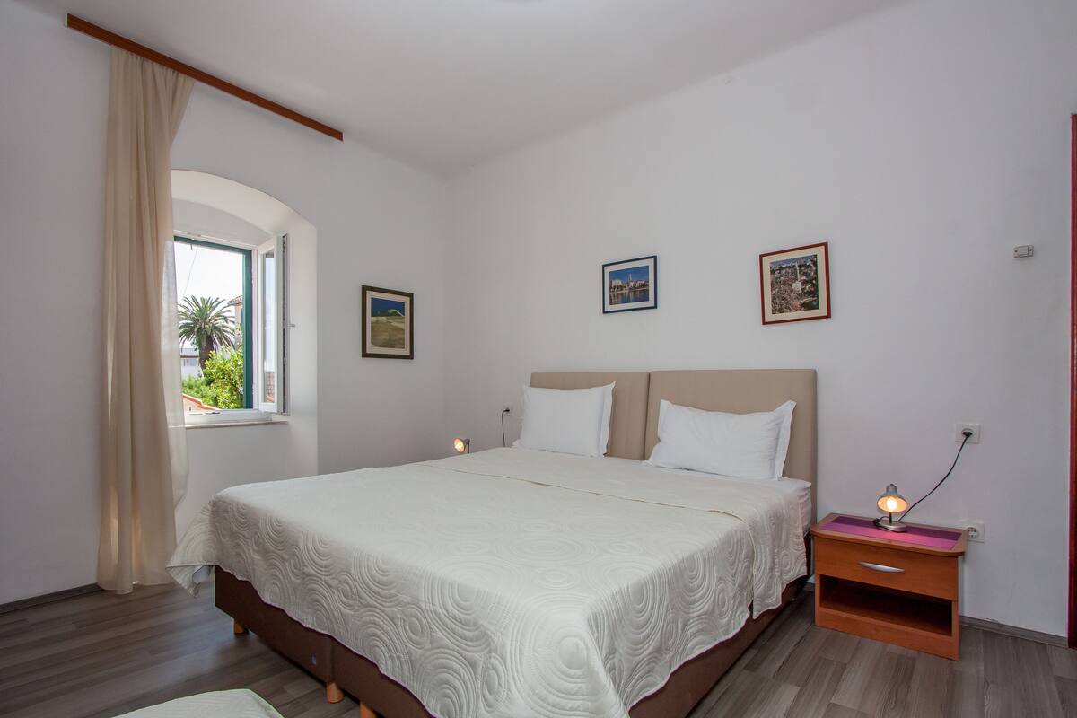 A bedroom with a bed, a nightstand with a lamp, and two framed pictures on the wall.