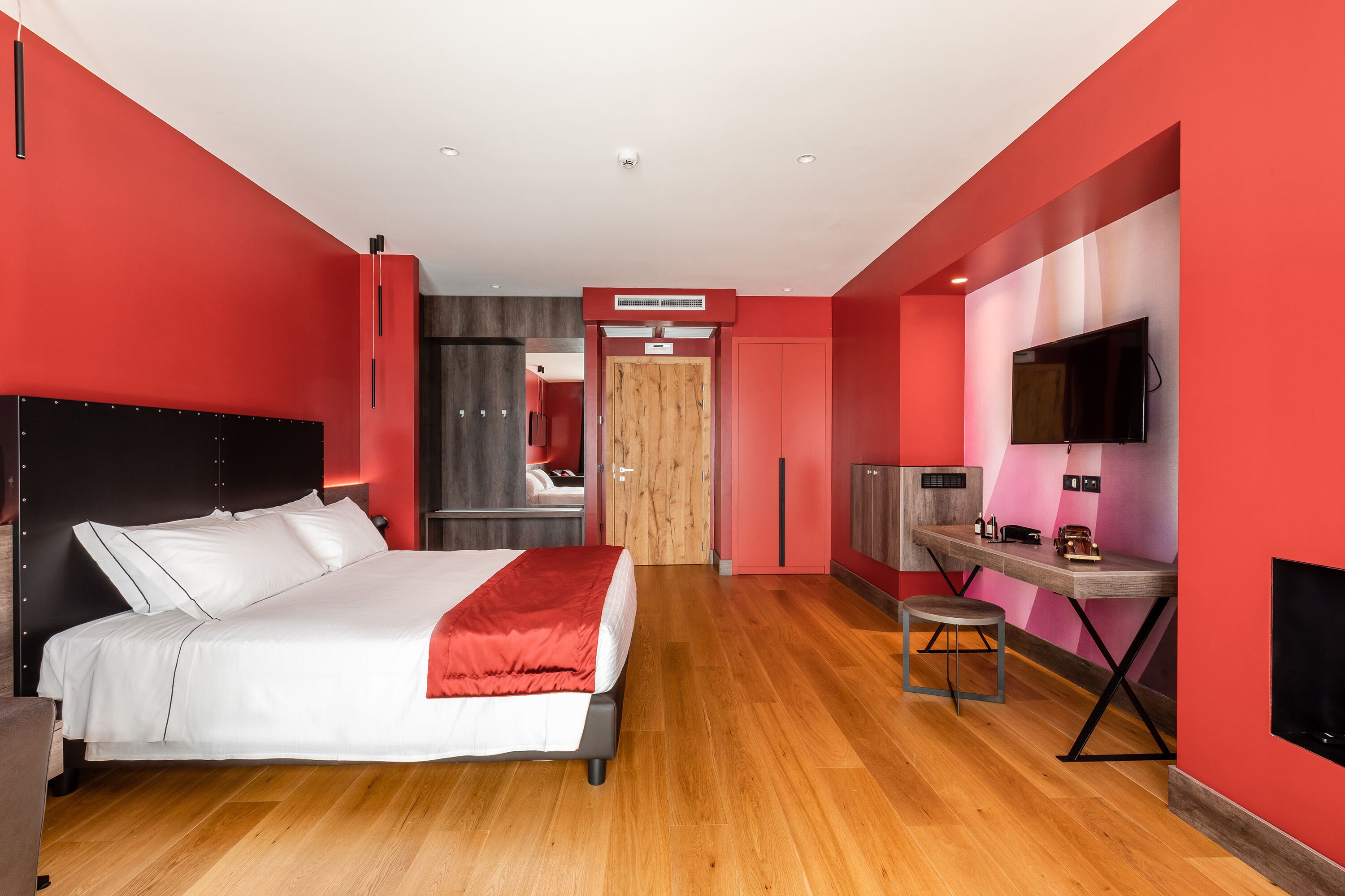 Een moderne slaapkamer met een groot bed, een bureau en een televisie.