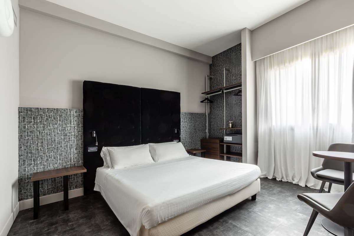 Ein modernes Hotelzimmer mit einem großen Bett, einem Schreibtisch und einem Sessel.