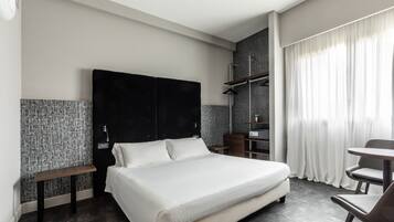Ein modernes Hotelzimmer mit einem großen Bett, einem Schreibtisch und einem Sessel.