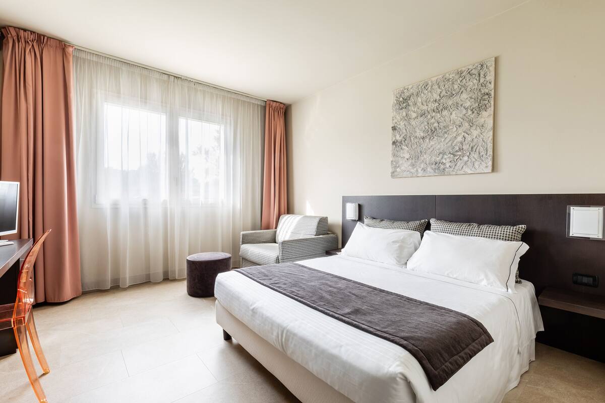 Ein modernes Hotelzimmer mit einem großen Bett, einem Schreibtisch und einem Sessel.