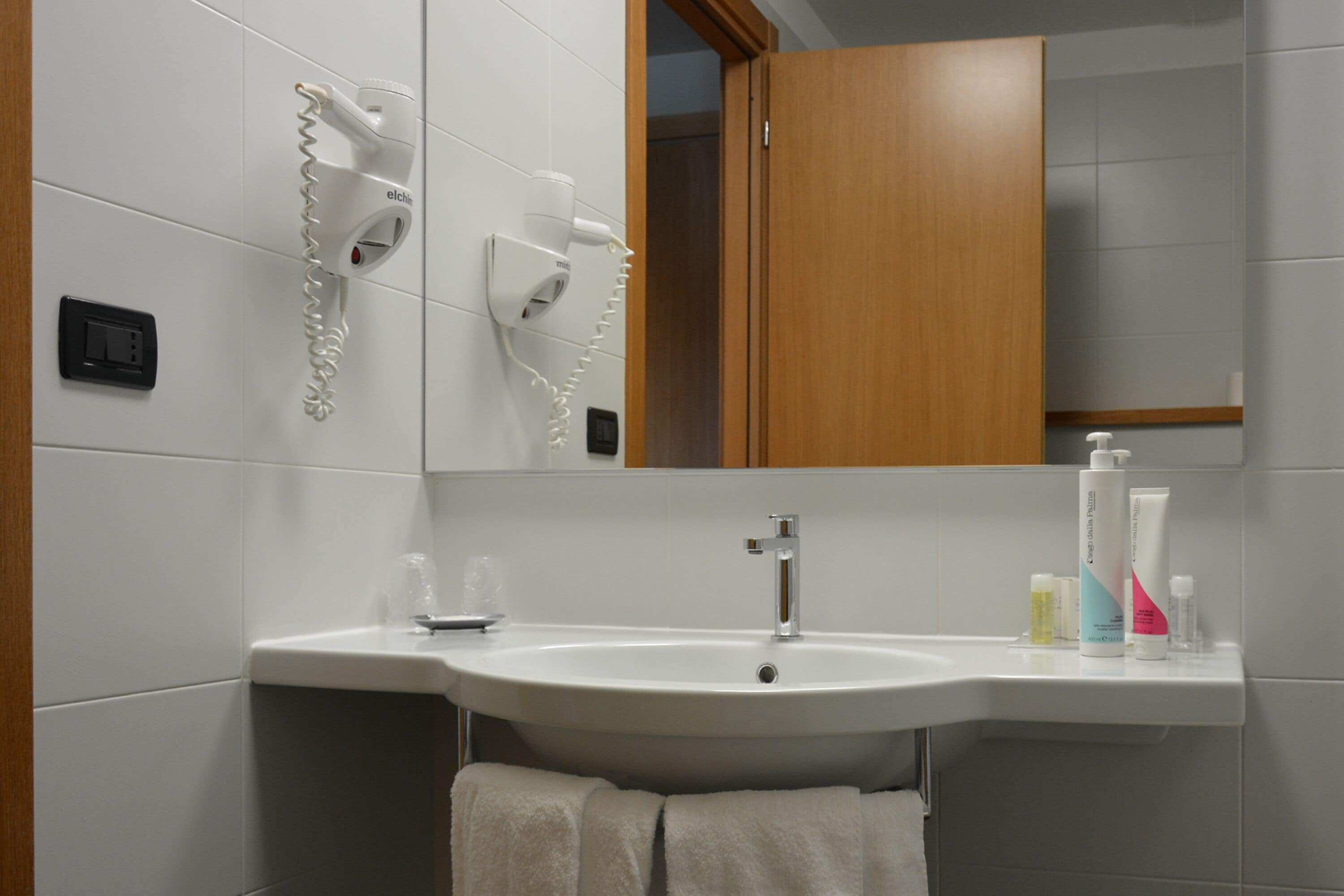 A bathroom with a sink, a hairdryer, and a mirror.