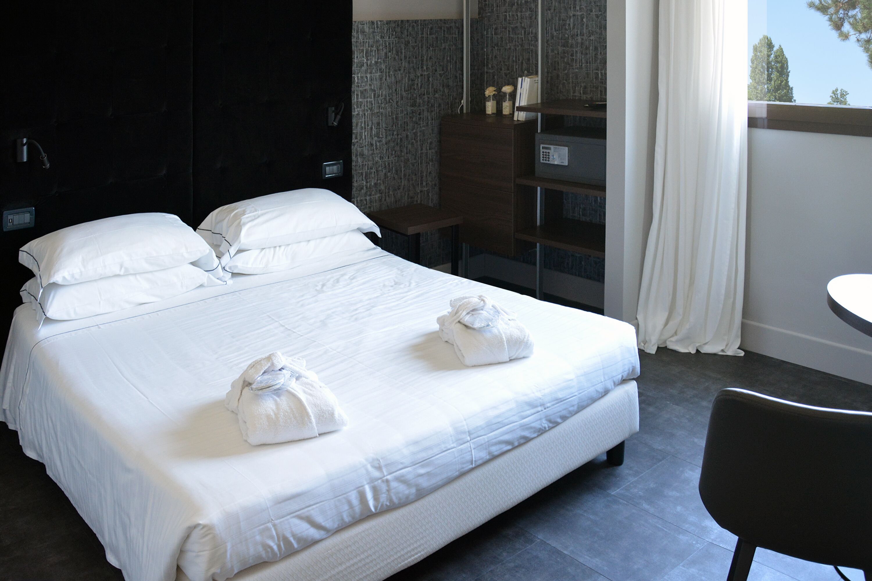 Una habitación de hotel con una cama grande, un escritorio pequeño, una silla y una ventana con cortinas.
