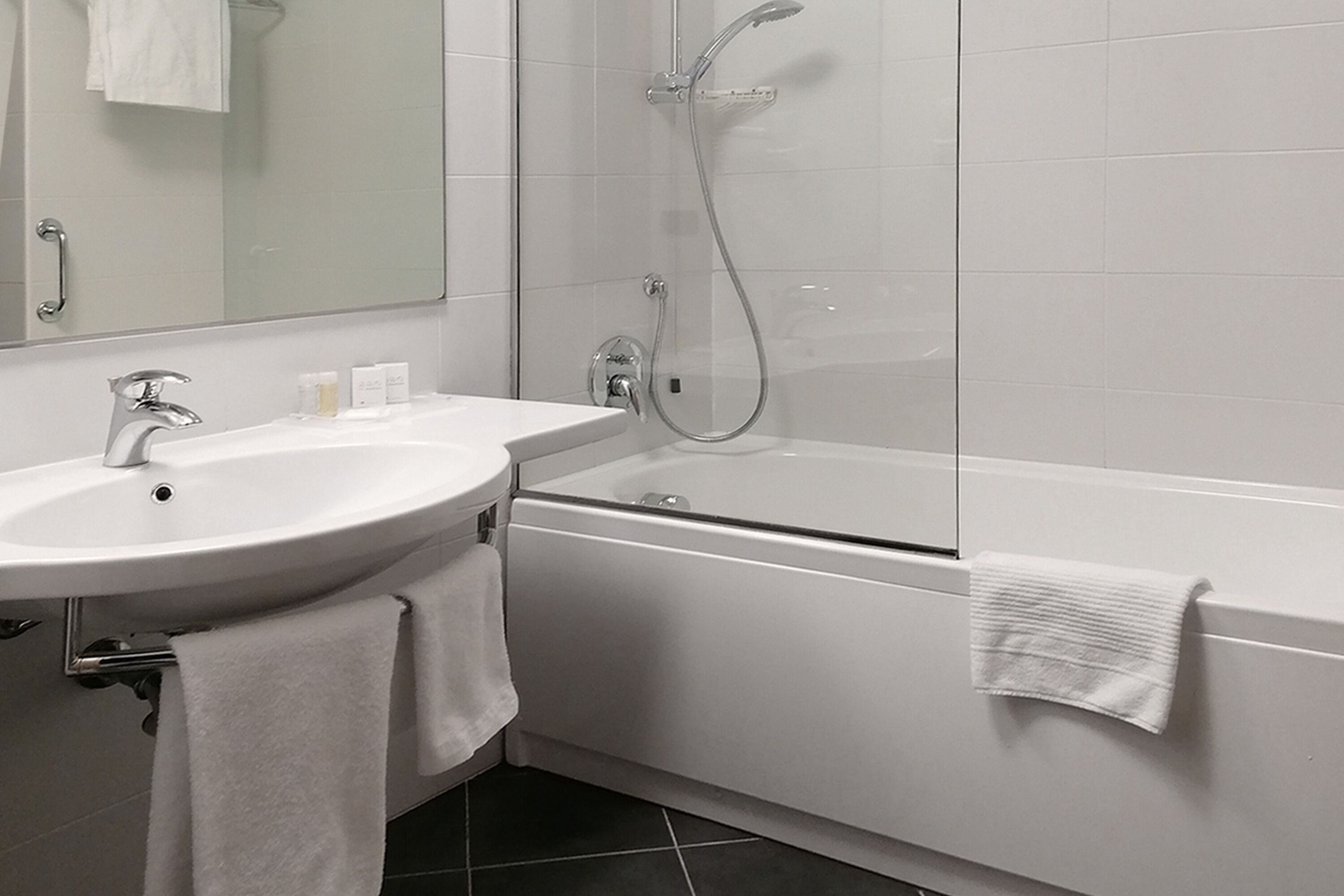 A modern bathroom with a white sink, mirror, and bathtub.