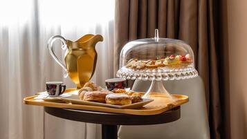 A tray with pastries, a pitcher, and a covered dessert stand on a table.