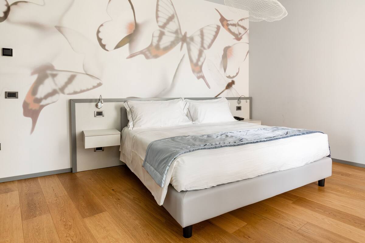 Ein modernes Schlafzimmer mit einem Bett, Nachttischen und einer Wand mit Schmetterlingsmotiven.