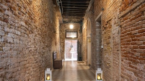 A corridor with checkered flooring, brick walls, and two lit lanterns. - Dimora al Doge Beato Vista Canale (Venice)