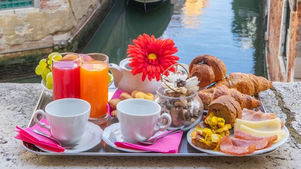A tray with breakfast items and a gondola in a narrow waterway, surrounded by historic buildings. - Dimora al Doge Beato Vista Canale (Venice)