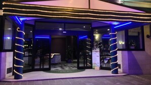 L’entrée d’un hôtel, dotée d’un espace abrité, de portes vitrées et d’un éclairage décoratif.