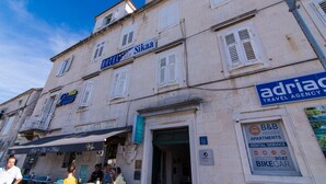 A building with a sign for 'Hotel Vila Vila' and 'Sikaa'. It has multiple windows with shutters, a balcony, and a sign for 'B&B Apartments Rental Service' including scooter and bike rental. - Vila Liza (Trogir)